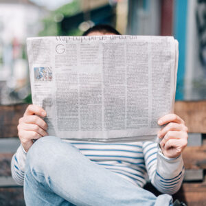 Photo of a person sitting and reading a newspaper