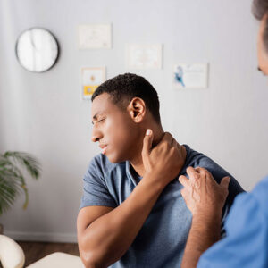 Staff member examining a patient's shoulder while the patient winces in pain