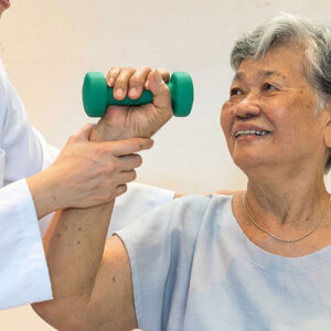 Nurse assisting a smiling patient lifting a handheld weight