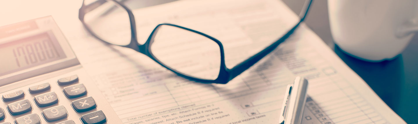 A photo of glasses laying on top of forms with a calculator and pen