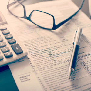 A photo of glasses laying on top of forms with a calculator and pen